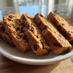 Four thick slices of golden brown Gluten-Free Chocolate Chip Biscotti arranged on a small white plate.