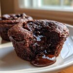 Close-up of a Gluten-Free Chocolate Lava Brownie Cup with molten chocolate oozing out onto a white plate.