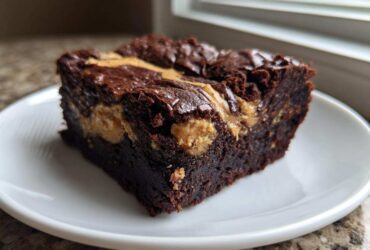 A close-up of a rich, fudgy Gluten-Free Chocolate Peanut Butter Swirl Brownies square on a white plate.