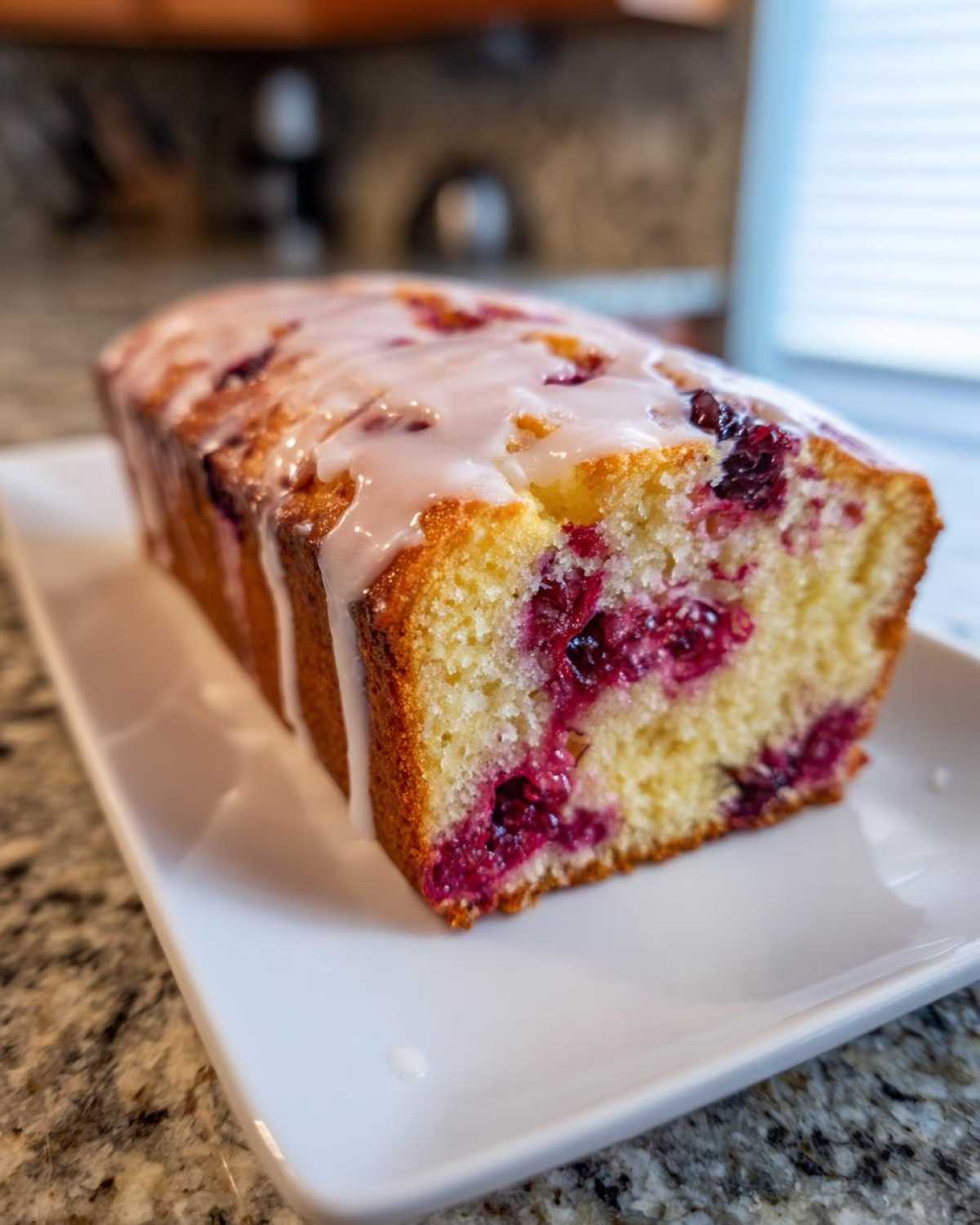Close-up of a slice of Gluten-Free Lemon Berry Yogurt Cake drizzled with white lemon glaze.
