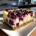 A close-up of a single serving of Gluten-Free Lemon Blueberry Cheesecake Squares on a white plate.