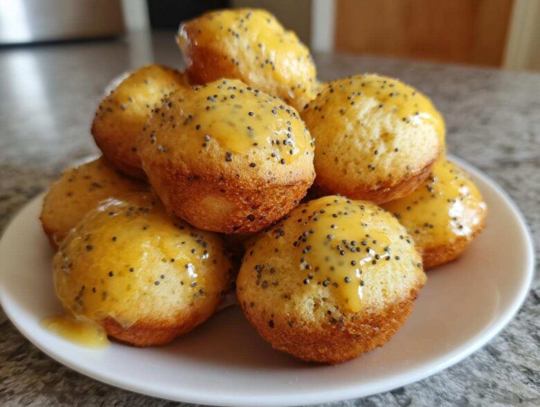 A stack of freshly baked Gluten-Free Lemon Poppy Seed Donut Holes topped with a bright yellow lemon glaze and poppy seeds.