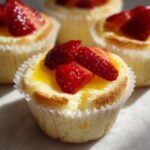 Close-up of a Gluten-Free Lemon Strawberry Angel Food Cup topped with bright yellow lemon curd and fresh sliced strawberries.