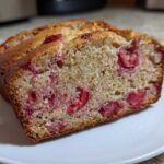 Close-up of a moist slice of Gluten-Free Strawberry Banana Bread showing bright red strawberry pieces throughout the crumb.