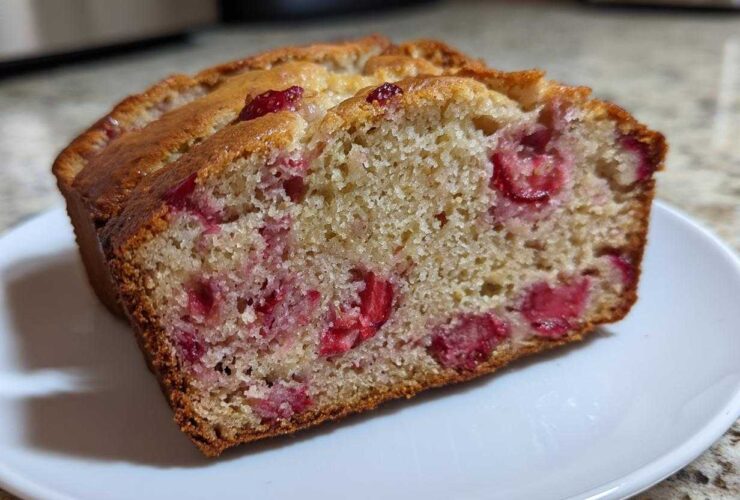Close-up of a moist slice of Gluten-Free Strawberry Banana Bread showing bright red strawberry pieces throughout the crumb.