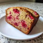 Two slices of moist Gluten-Free Strawberry Banana Bread featuring bright red berries served on a white plate.