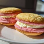 Two delicious Gluten-Free Strawberry Lemon Whoopie Pies with pink and white filling sitting on a white plate.