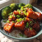 A close-up of a Honey Sriracha Chicken Rice Bowls featuring glazed chicken pieces, white rice, and steamed broccoli.