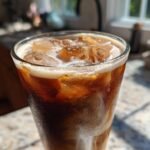 Close-up of a tall glass filled with Iced Brown Sugar Cinnamon Cold Brew, ice cubes, and condensation.