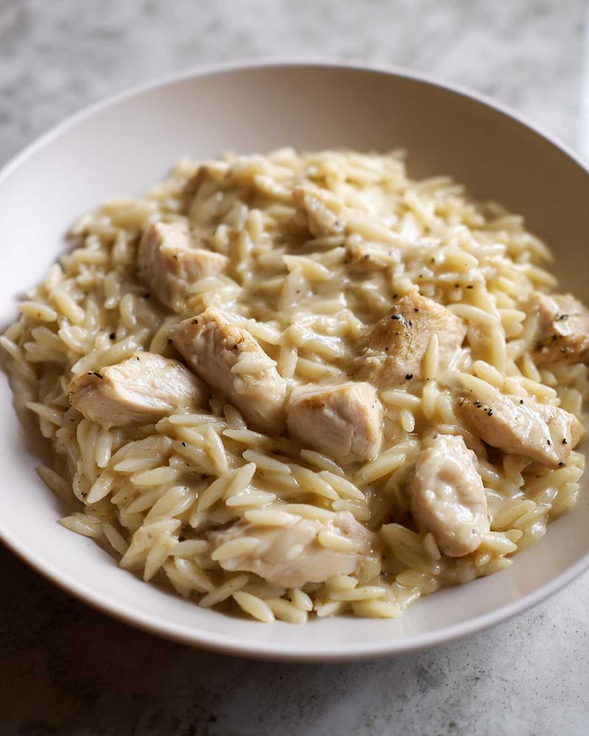 Close-up of a bowl filled with creamy Instant Pot Creamy Chicken and Orzo, featuring tender chicken pieces.
