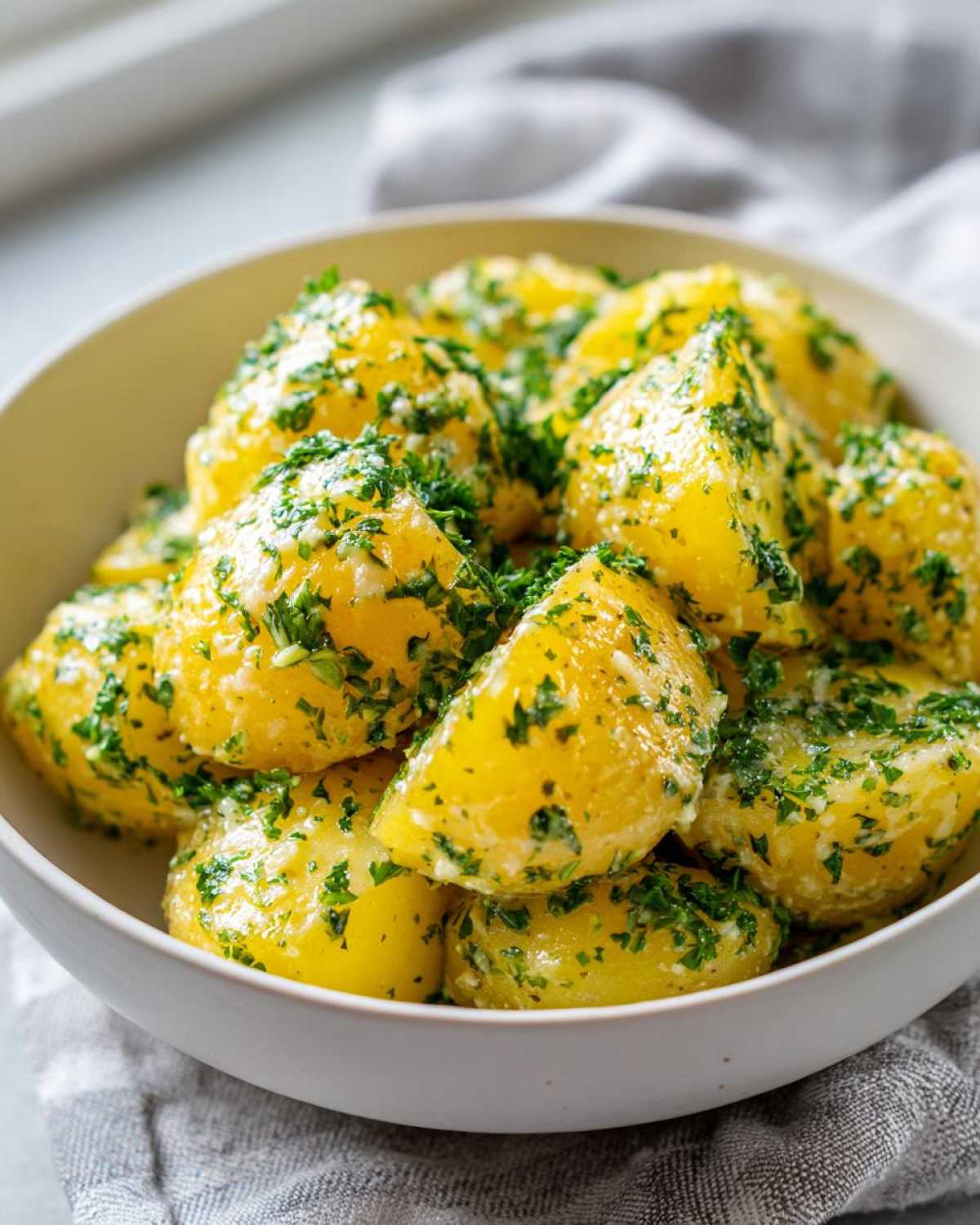 A close-up of Instant Pot Creamy Garlic Butter Potatoes tossed in a rich, buttery sauce and topped generously with fresh chopped parsley.