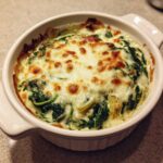 Close-up of baked Instant Pot Creamy Spinach Artichoke Dip with melted, browned cheese topping.