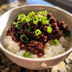 Close-up of Instant Pot Korean Beef and Rice Bowls topped with green onions and sesame seeds.