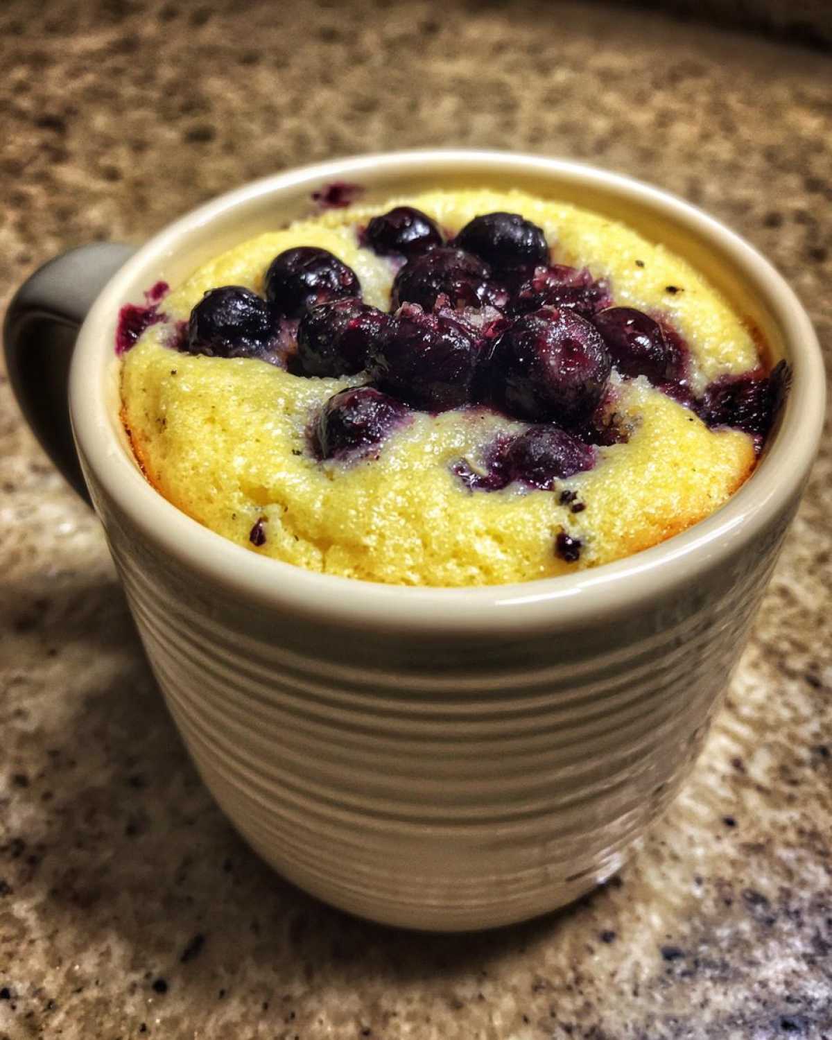 Close-up of a freshly baked Keto Blueberry Lemon Mug Cake topped with whole blueberries.