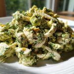 Close-up of Keto Creamy Avocado Chicken Salad piled high on a white plate, featuring shredded chicken and green avocado dressing.