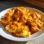 Close-up of tender chicken pieces coated in rich, orange, creamy sauce from the Keto Creamy Butter Chicken Skillet recipe.