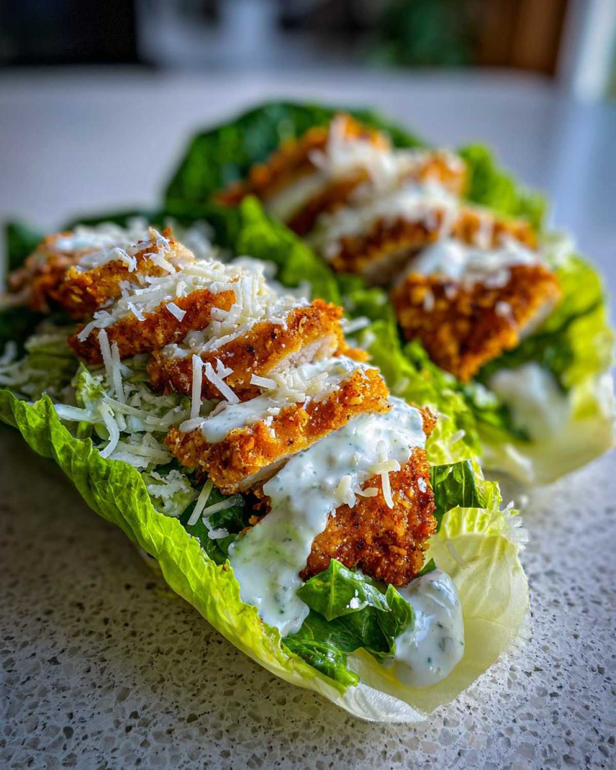 Close-up of Keto Crispy Chicken Caesar Salad Wraps made with lettuce cups, crispy chicken, Caesar dressing, and Parmesan cheese.