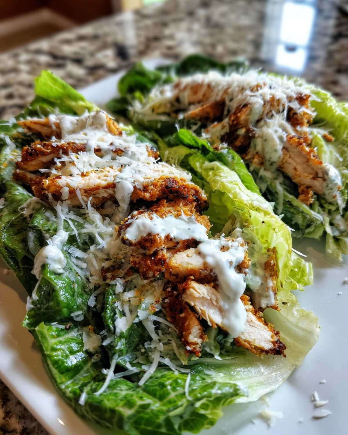 Two servings of Keto Crispy Chicken Caesar Salad Wraps made using large romaine lettuce leaves as the wrap base.