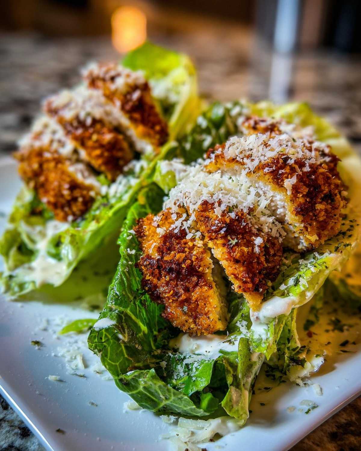 Two servings of Keto Crispy Chicken Caesar Salad Wraps featuring crispy chicken pieces over romaine lettuce with Caesar dressing and grated Parmesan.