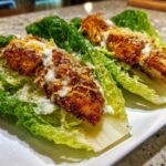 Close-up of Keto Crispy Chicken Caesar Salad Wraps made with crispy chicken strips on romaine lettuce leaves with Caesar dressing.