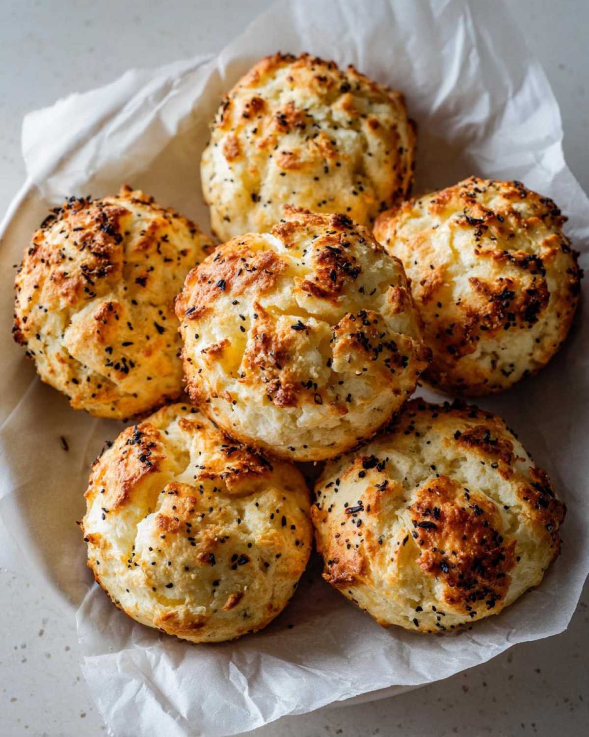 Six golden-brown Keto Everything Bagel Cloud Bread portions stacked in parchment paper.