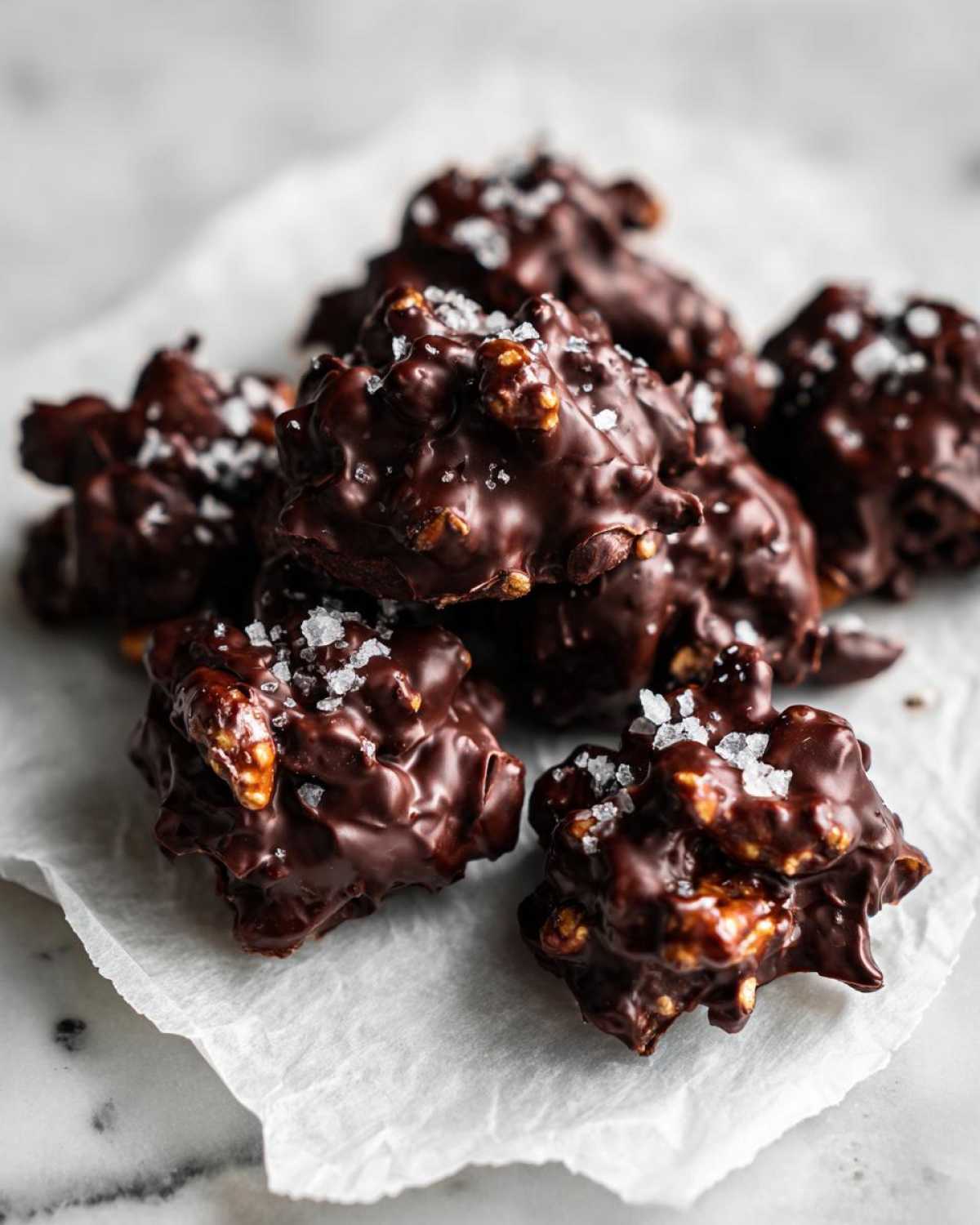 Close-up of several No-Bake Chocolate Covered Pretzel Clusters sprinkled with sea salt.