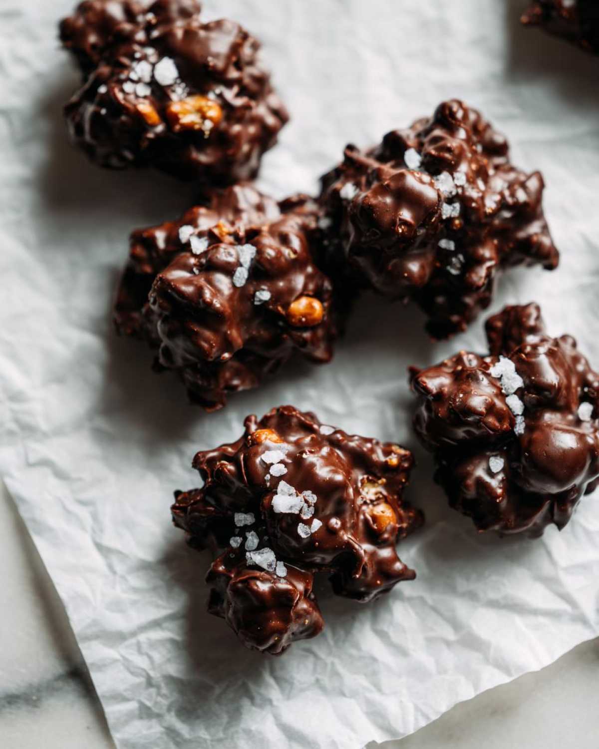 Close-up of several No-Bake Chocolate Covered Pretzel Clusters sprinkled with flaky sea salt.