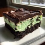 A rich slice of No-Bake Chocolate Mint Icebox Bars showing a dark crust, mint layer, and chocolate topping.