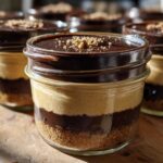 Close-up of layered No-Bake Chocolate Peanut Butter Pie Jars with crust, peanut butter filling, chocolate ganache, and crumble topping.