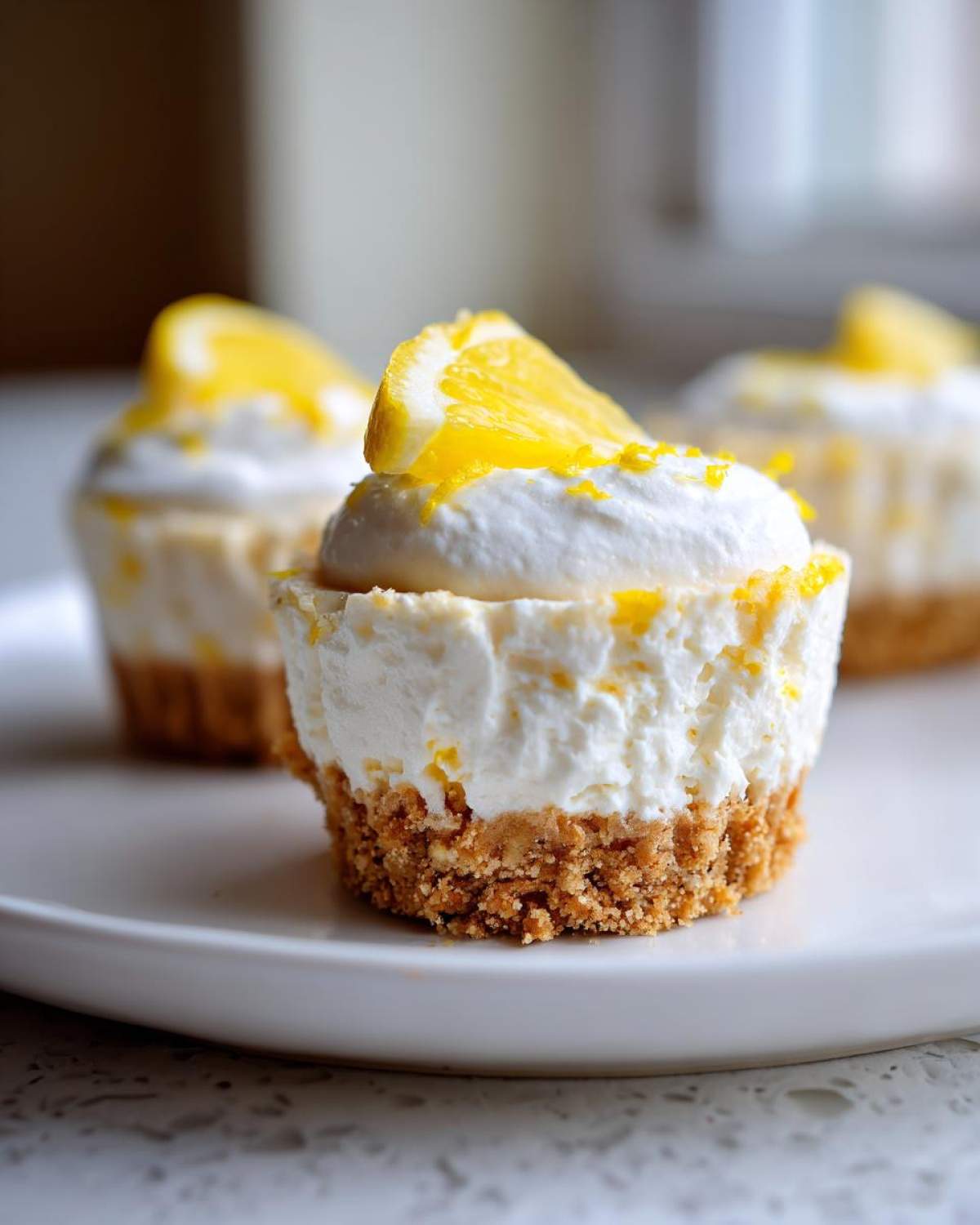A close-up of a No-Bake Lemon Coconut Cheesecake Cup with a graham cracker crust, creamy filling, and lemon garnish.
