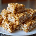 A stack of chewy No-Bake Peanut Butter Rice Cereal Bars coated in a glossy peanut butter mixture.