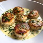 Five perfectly seared One-Pan Creamy Lemon Butter Scallops swimming in a rich, creamy lemon butter sauce garnished with fresh parsley.