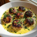 Six browned One-Pan Creamy Lemon Garlic Turkey Meatballs served in a rich, yellow cream sauce and garnished with fresh parsley.