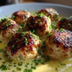 Close-up of browned One-Pan Creamy Lemon Garlic Turkey Meatballs submerged in a rich, yellow sauce and garnished with fresh parsley.