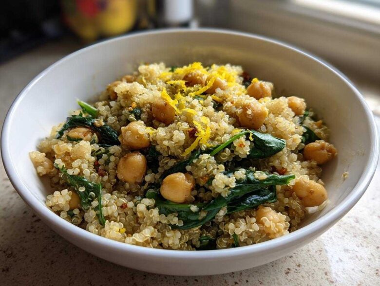 Close-up of a white bowl filled with the One Pot Chickpea Quinoa Recipe, featuring chickpeas, spinach, and lemon zest.