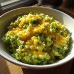 Close-up of a bowl filled with One-Pot Creamy Broccoli Cheddar Rice topped with melted cheddar cheese.