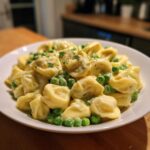 A white bowl filled with One-Pot Creamy Garlic Butter Tortellini and Peas, garnished with parsley.