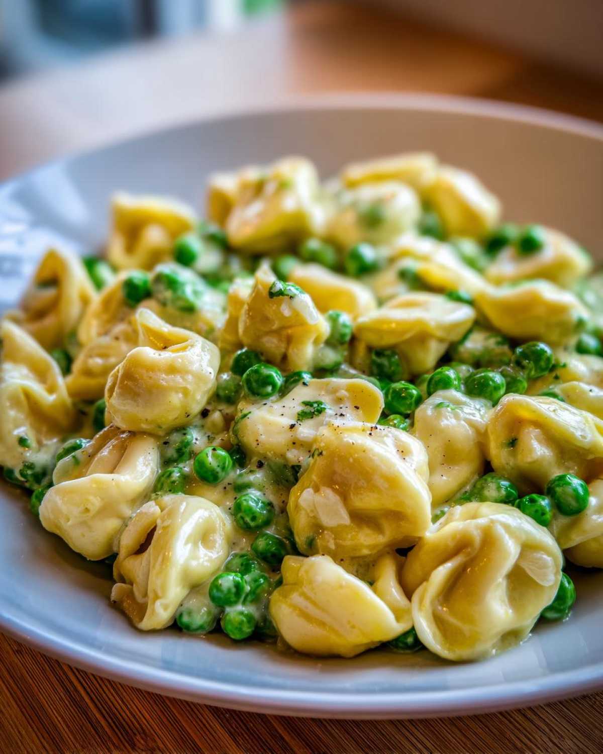 Close-up of One-Pot Creamy Garlic Butter Tortellini and Peas coated in a rich sauce.