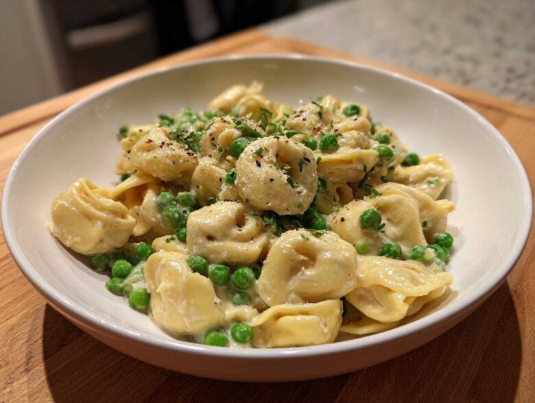 A close-up of One-Pot Creamy Garlic Butter Tortellini and Peas served in a white bowl, garnished with parsley.