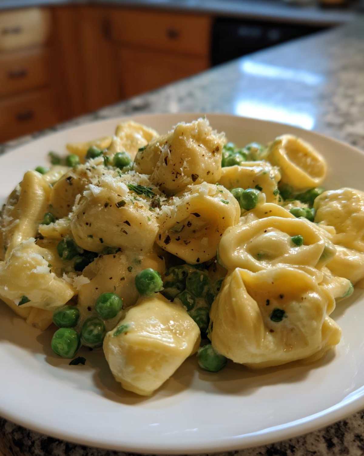 A close-up of One-Pot Creamy Garlic Butter Tortellini and Peas topped with grated cheese and herbs.