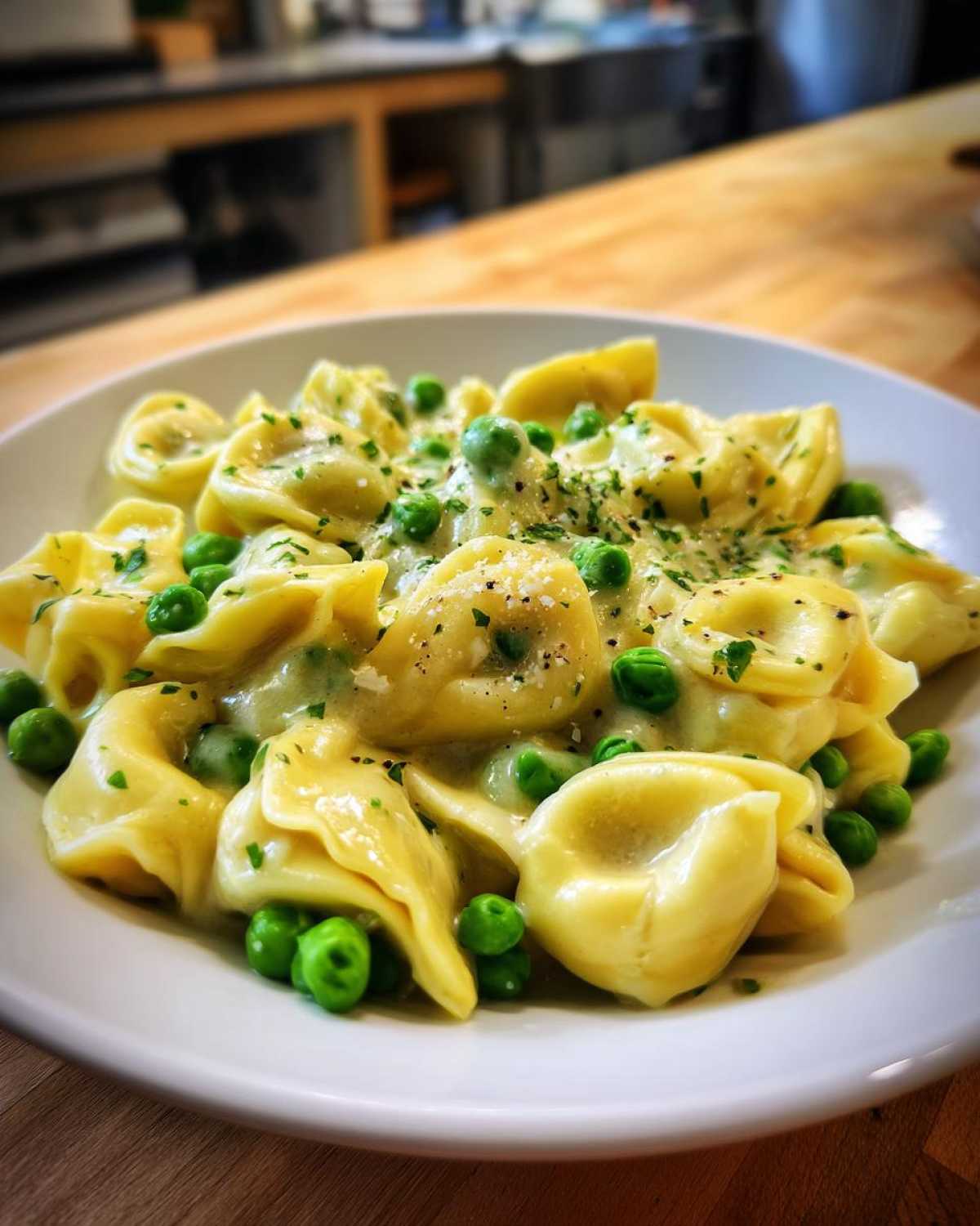 Close-up of One-Pot Creamy Garlic Butter Tortellini and Peas served in a white bowl, garnished with parsley.