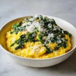 A close-up of One-Pot Creamy Spinach Parmesan Polenta topped with wilted spinach and grated Parmesan cheese.