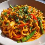 A vibrant bowl of One-Pot Creamy Thai Red Curry Noodles topped with fresh cilantro and green beans.