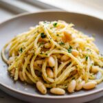 A close-up of One-Pot Creamy White Bean Lemon Pasta featuring spaghetti, white beans, and fresh parsley.