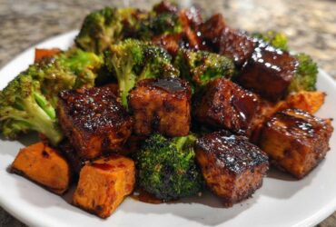 Close-up of glazed Sheet Pan Crispy Honey Mustard Tofu cubes served with roasted broccoli florets and sweet potato chunks.