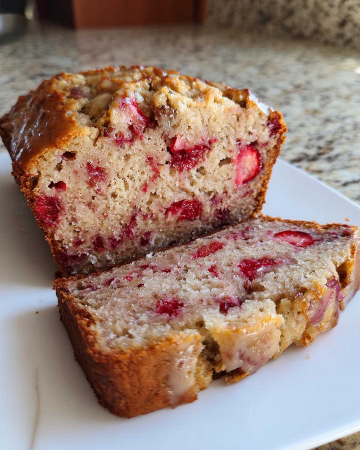 Close-up of a loaf of Gluten-Free Strawberry Banana Bread, sliced to show moist interior packed with strawberries.