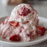 A close-up of scoops of Vegan Creamy Strawberry Oat Milk Ice Cream with visible chunks of fresh strawberries.