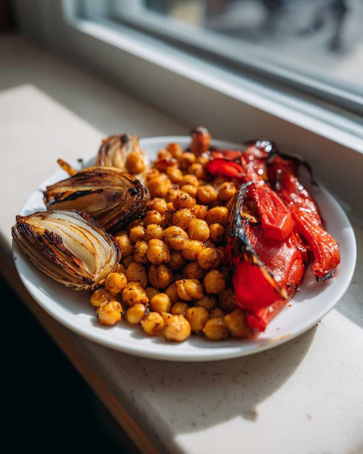 Plate of roasted chickpeas, charred onion wedges, and red peppers from the Vegan One-Pan Chickpea Shawarma Sheet Bake.