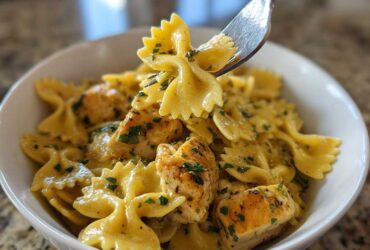 Close-up of Cowboy butter lemon bowtie chicken pasta being lifted by a fork from a white bowl.