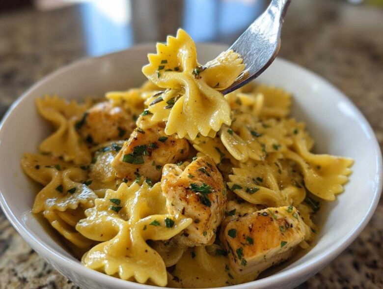 Close-up of Cowboy butter lemon bowtie chicken pasta being lifted by a fork from a white bowl.
